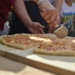 Мужчина режет пиццу на сырном фестивале в Истре