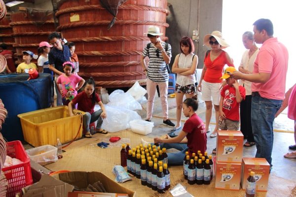 Туристы наблюдают за процессом изготовления и упаковки рыбного соуса ныок-мам